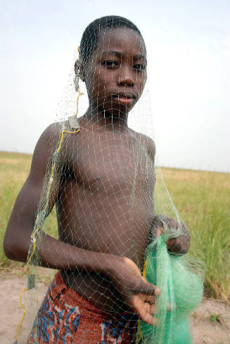 Borderless Captivity, Boy with fishing net heads out to Lake Volta, works...