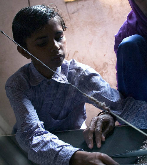 Borderless Captivity, Boy works alongside mother at sari loom...