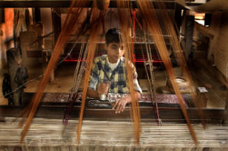 Borderless Captivity, Young boy falling asleep at sari loom...