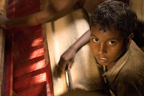 Borderless Captivity, Young boy at sari loom, works alongside...